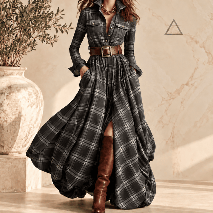 Robe longue Constance en coloris Ardoise, à carreaux gris foncé et gris clair, portée avec une ceinture brune et des bottes hautes.
