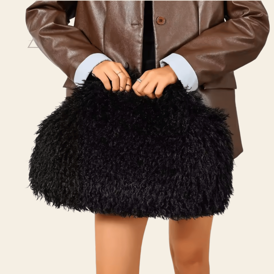 Sac Soline oversize en coloris noir, porté à la main avec une veste en cuir brun.