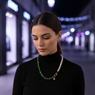 Collier Midnight Reflections porté sur un col roulé noir, avec perles vertes, section de perles blanches et fermoir doré sur le côté.