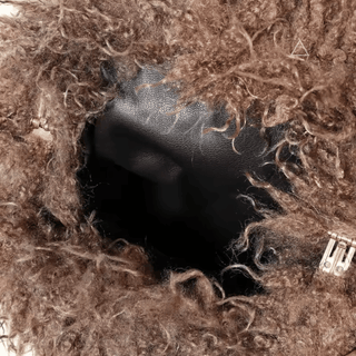 Détail de l’intérieur noir du sac Soline, entouré de sa texture bouclée brun chocolat et de son fermoir.
