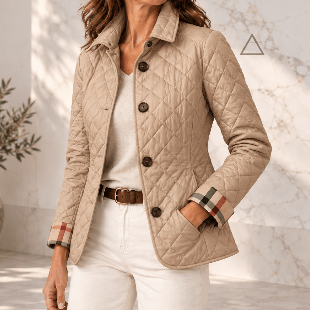 Veste matelassée Margaux en beige sable, portée avec un pantalon écru, avec fermeture boutonnée et revers de poignets à carreaux.
