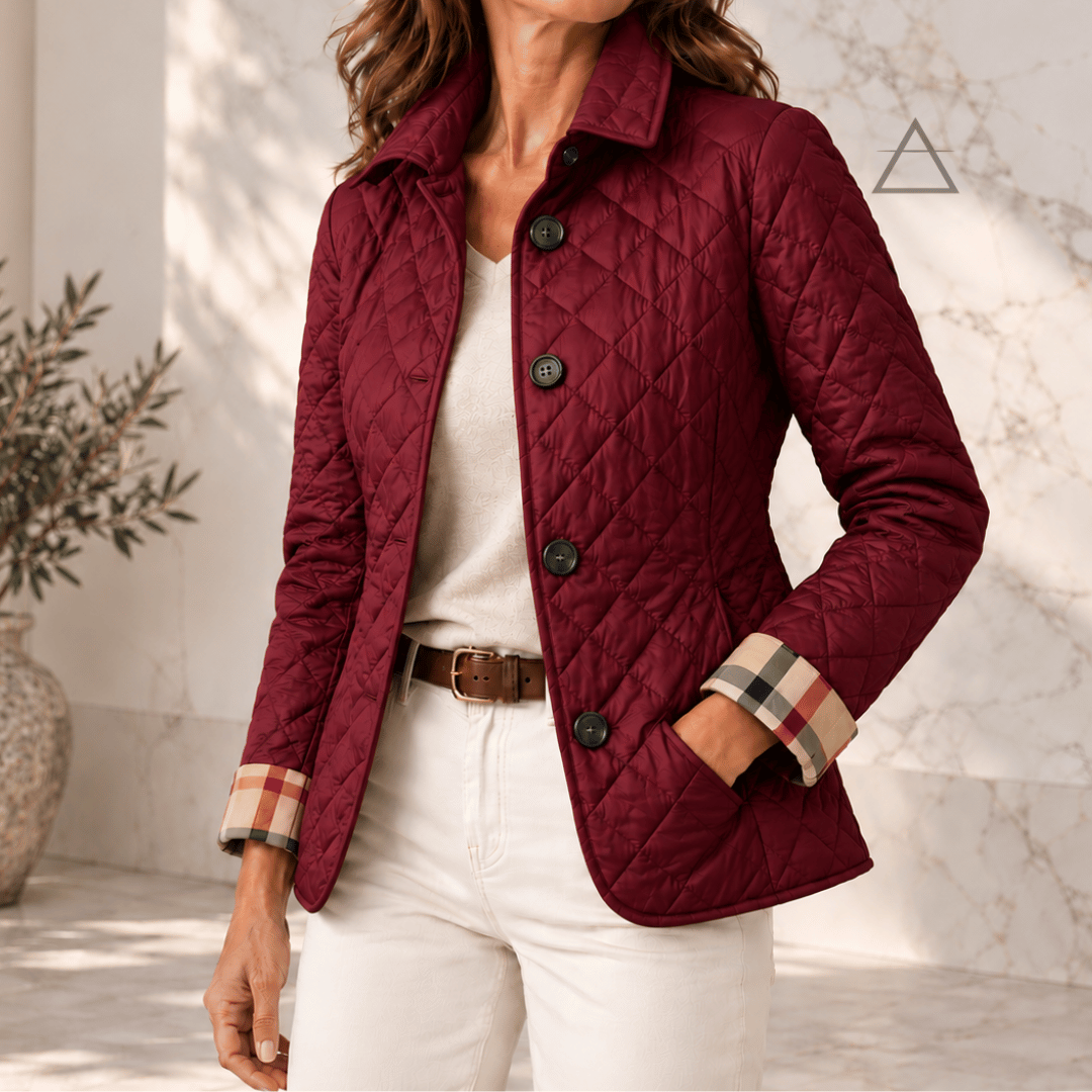 Veste matelassée Margaux en bordeaux, portée avec un pantalon écru, avec fermeture boutonnée et revers de poignets à carreaux.