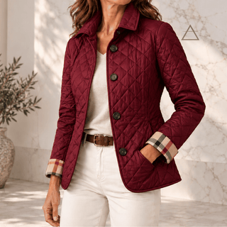 Veste matelassée Margaux en bordeaux, portée avec un pantalon écru, avec fermeture boutonnée et revers de poignets à carreaux.