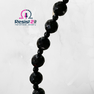 Gros plan sur les perles noires facettées du collier Ocean Midnight, séparées par de petites perles noires.