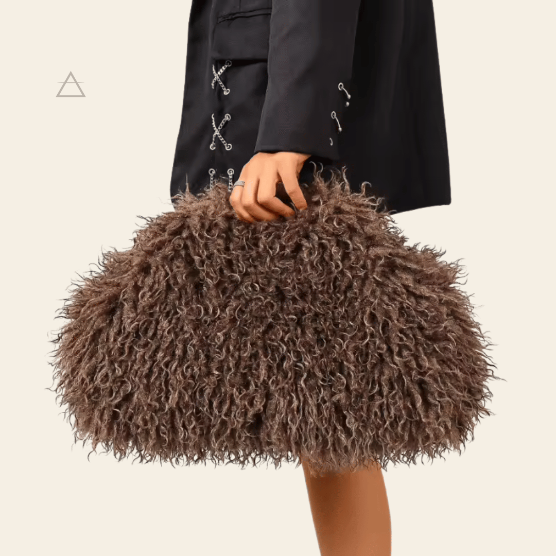 Sac Soline oversize en coloris chocolat, porté à la main avec une veste en cuir brun.