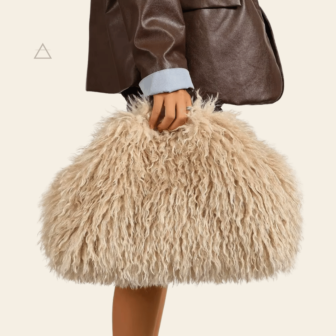 Sac Soline oversize en coloris crème, porté à la main avec une veste en cuir brun.