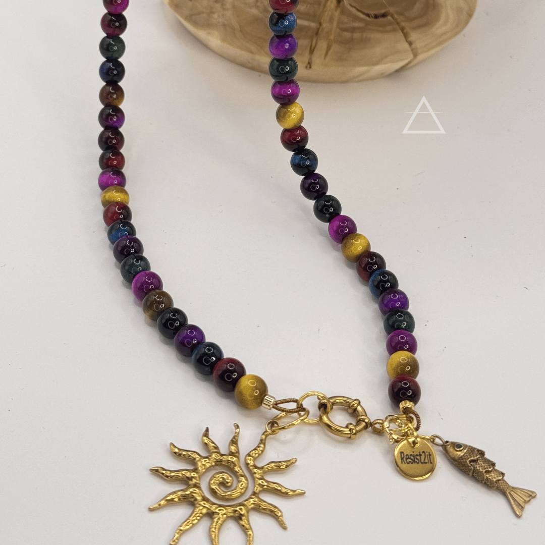 Détail du collier SOLSTICE : perles multicolores, pendentifs soleil et poisson dorés et médaille Resist2it.