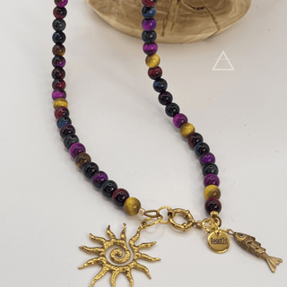 Détail du collier SOLSTICE : perles multicolores, pendentifs soleil et poisson dorés et médaille Resist2it.