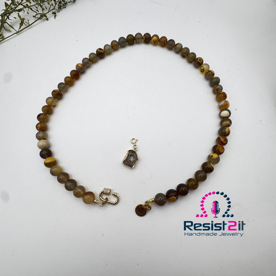 Collier Unspoken ouvert sur fond blanc, avec son pendentif en agate détaché au centre.