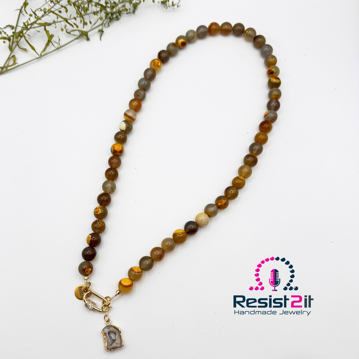 Vue complète du collier Unspoken sur fond blanc, avec son fermoir à l’avant et son pendentif en agate.