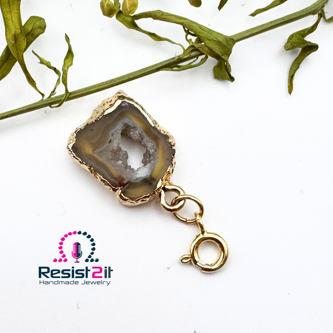 Pendentif amovible d’Unspoken en tranche d’agate, avec bordure de teinte dorée et petit fermoir rond.